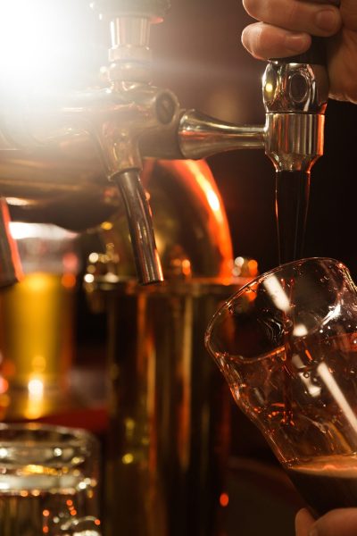 Close up of a bartender pouring beer while standing at the bar counter